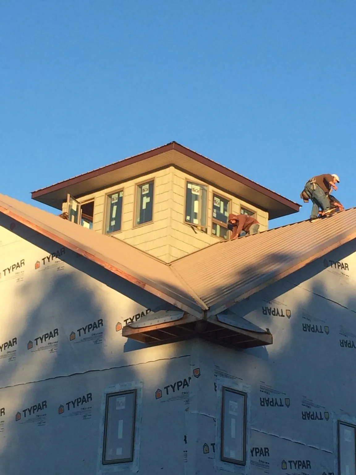 Roofers working around a rooftop cupola on a new metal roof at sunset — Roof Waterproofing in Preston by Roofing Brothers